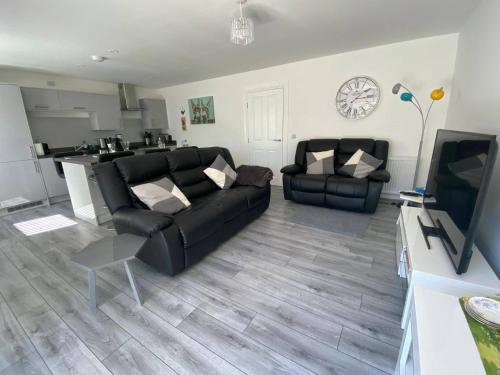 a living room with a black couch and a tv at Beautiful Riverside Holiday Home in Callander