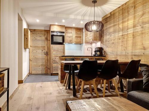 - une cuisine avec des murs en bois, une table et des chaises dans l'établissement Superbe 2 Pièces + Cabine Rénové, Pied des Pistes, Val d'Isère, 6 Pers., Parking, Balcon Sud - FR-1-518-42, à Val dʼIsère