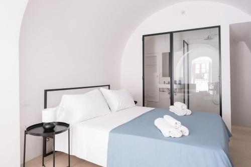 - une chambre blanche avec un lit et des serviettes dans l'établissement I 5 Archi di Via Ducezio, à Noto