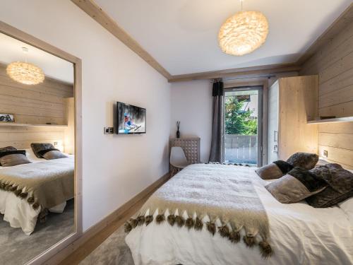 une chambre avec deux lits et un grand miroir dans l'établissement Appartement moderne au cœur de Courchevel Village, proche commerces et pistes, avec espace fitness. - FR-1-562-36, à Courchevel