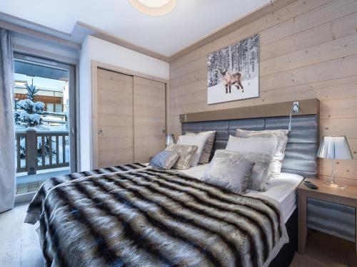 a bedroom with a large bed with a striped blanket at Appartement moderne à Courchevel Village, près des commerces et pistes, parking et salle de fitness inclus - FR-1-562-38 in Courchevel