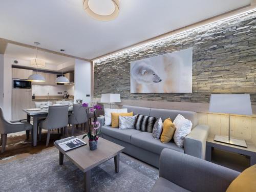 un salon avec un canapé et un mur en pierre dans l'établissement Appartement moderne à Courchevel Village, près des commerces et pistes, parking et salle de fitness inclus - FR-1-562-38, à Courchevel