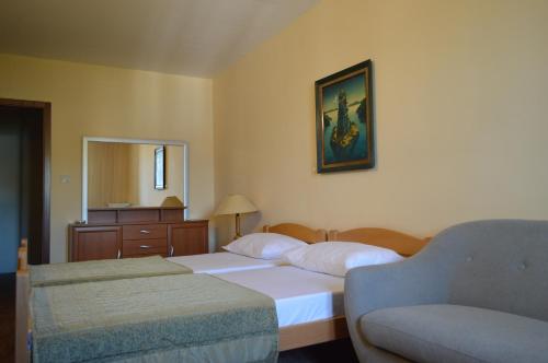 a bedroom with two beds and a chair and a mirror at Ambassador Apartments in Petrovac na Moru