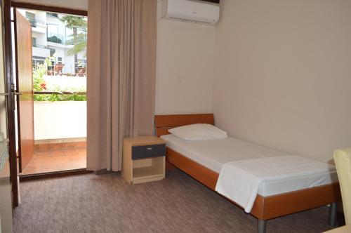 a small bedroom with a bed and a balcony at Ambassador Apartments in Petrovac na Moru
