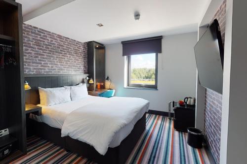 um quarto com uma cama grande e uma parede de tijolos em Village Hotel Glasgow em Glasgow