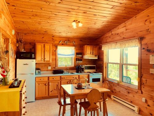 una cocina con armarios de madera y una mesa en una cabaña en Eagle Valley Cottages, en Queensport