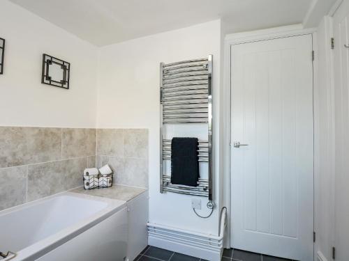 a white bathroom with a tub and a window at Lily Cottage in Downham Market