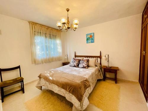 um quarto com uma cama e um lustre em Agradable casa con chimenea, en zona tranquila de Sanabria em Barrio de Lomba