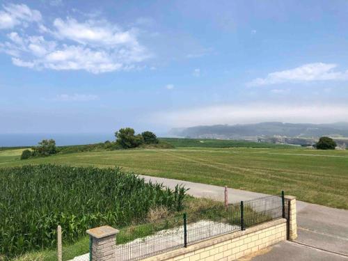 a field with a fence next to a road at El Ribero de Langre in Langre