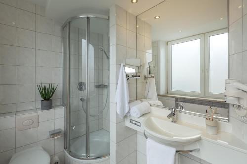 a white bathroom with a sink and a shower at Select Hotel Tiefenthal in Hamburg