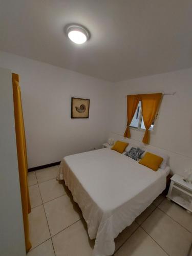 1 dormitorio con 1 cama blanca grande con almohadas amarillas en Paradise01, en Saint Martin