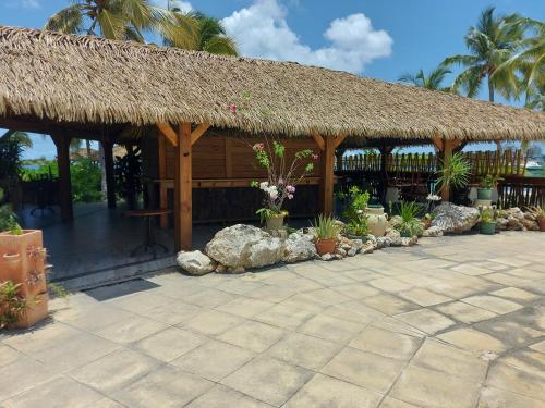 un bâtiment avec un toit de paille et une terrasse dans l'établissement Paradise01, à Les Terres Basses