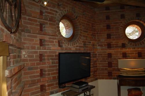 a living room with a brick wall with a flat screen tv at The Hyde Dovecote Kinver in Stourbridge