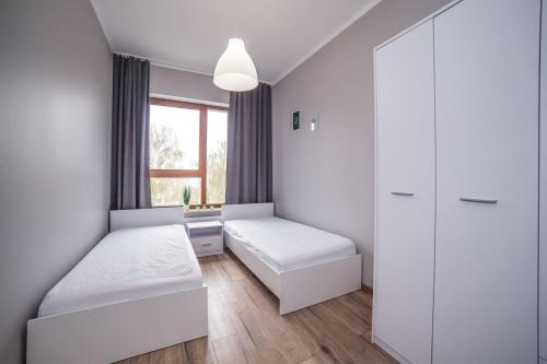 a small room with two beds and a window at Apartament Opera Park przy ul. Kołobrzeskiej in Olsztyn