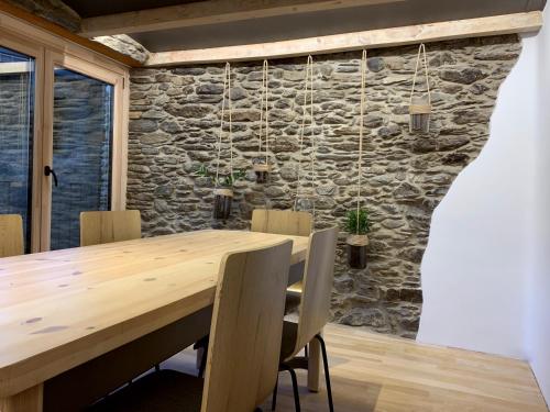 una mesa de madera y sillas en una habitación con una pared de piedra en Cal Potablanc, en Canillo