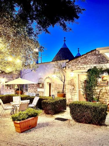 a stone house with a patio with chairs and an umbrella at Mirella Charming in Alberobello