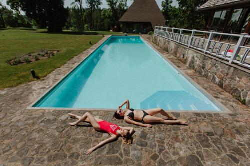 two women laying on the ground in a swimming pool at Mini hotel in Kuldīga