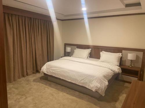 a bedroom with a bed with white sheets and pillows at الدور العالية- للوحدات السكنية in Khamis Mushayt