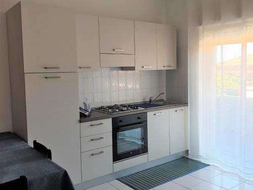 uma cozinha com armários brancos e um forno com placa de fogão em Baia Alcantara Apartments (Old Bay Group) em Giardini Naxos