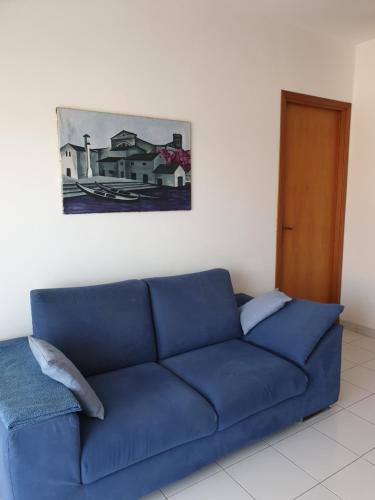 um sofá azul numa sala de estar com um quadro na parede em Baia Alcantara Apartments (Old Bay Group) em Giardini Naxos