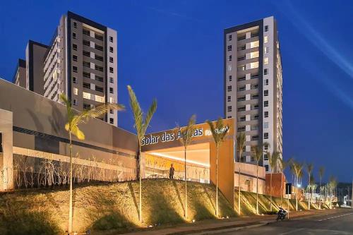 two tall buildings with palm trees in front of a street at APARTAMENTO OLIMPIA SOLAR DAS AGUAS in Olímpia