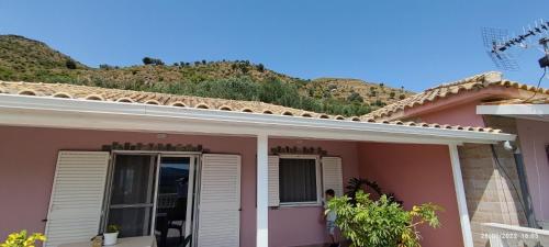 a pink house with a hill in the background at Phoenice's apartment in Finiq