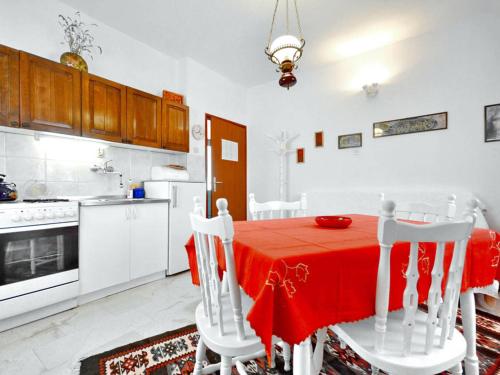 a white kitchen with a red table and chairs at Villa Povlja in Povlja
