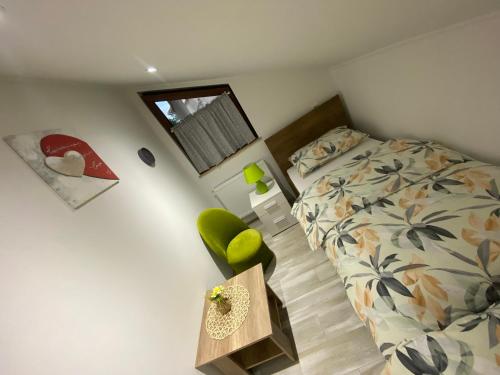 una piccola camera con letto e sedia verde di Apartman FILIP a Udbina