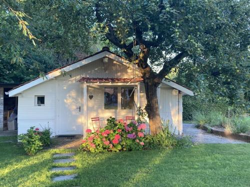 a small white shed with a tree in the yard at LE CHALET de LA LONGERE in Beuvry-Nord