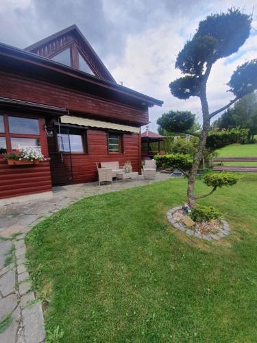 a house with a tree in front of a yard at Domek pod Królowem in Ustroń