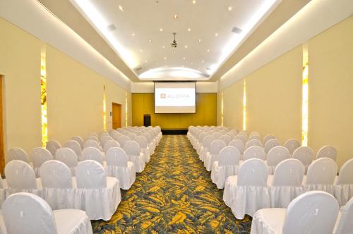 a conference room with white chairs and a projection screen at Gamma Colima Garden in Colima