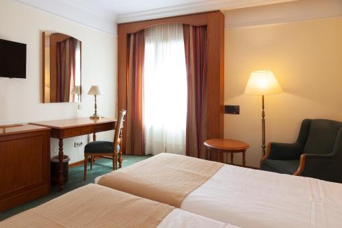 a hotel room with a bed and a desk at Hotel Hoyuela in Santander