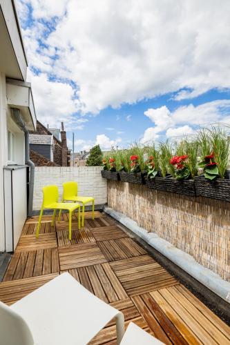 a patio with yellow chairs and a fence with flowers at Madrid Suites in Maastricht