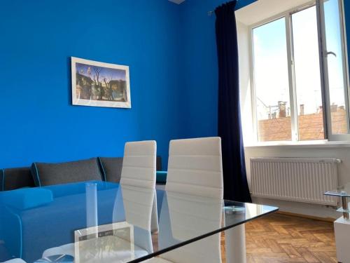 ein blaues Wohnzimmer mit einem Glastisch und weißen Stühlen in der Unterkunft Virmenski sobor apt high ceiling,not attic in Lwiw