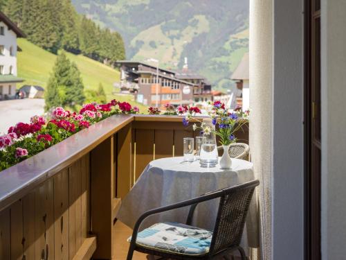 a table and chair on a balcony with flowers at Ferienwohnungen Rieser in Hainzenberg