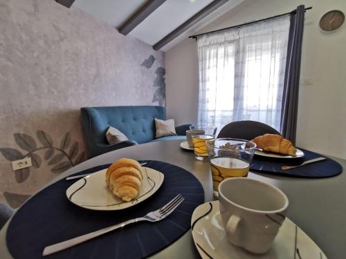 a table with two plates of croissants and drinks on it at New Nikolina 4 star in Mali Lošinj