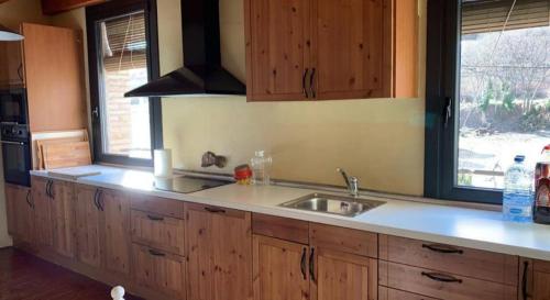 cocina con armarios de madera, fregadero y ventana en El Molí de Cal Pastisser, en Avellanes