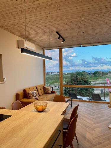 a kitchen and living room with a large window at Smėlėtas krantas in Svenele
