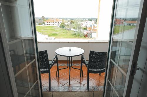 a table and chairs on a balcony with a window at Casal dos Cantos in Quinta do Anjo