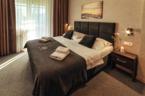 a bedroom with a large bed with two towels on it at Srebrny Bucznik Wellness & Restaurant in Istebna
