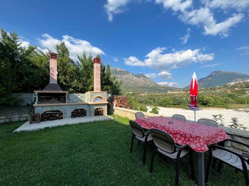a table and chairs with a fireplace in a yard at River Escape Villa - Private Beach, Scenic view & BBQ in Tepelenë
