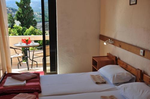 a bedroom with two beds and a balcony with a table at House Margot in Palekastron
