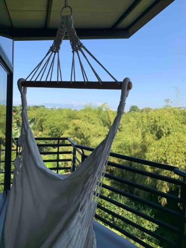 a hammock hanging from a porch with a view of a forest at Entre Bambús in Pereira