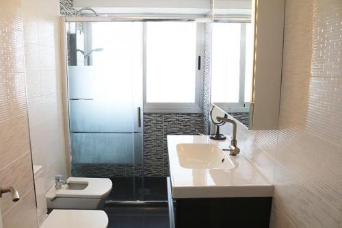 La salle de bains est pourvue d'un lavabo, de toilettes et d'une douche. dans l'établissement Appartement Rosa N&B met Groot Terras met Zeezicht -70m van Strand, à Calp