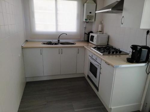 a small kitchen with a stove and a microwave at Apartamento acogedor en primera linea de playa in Denia
