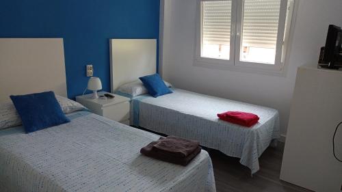 a bedroom with two beds with blue walls and two windows at Apartamento acogedor en primera linea de playa in Denia