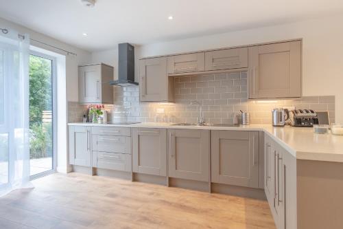 a kitchen with white cabinets and a large window at Snowdon Holiday Let, brand new home in the heart of Llanberis in Llanberis