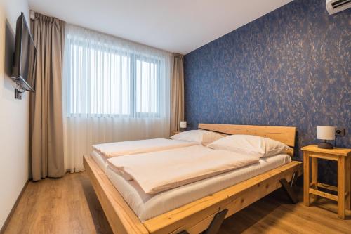 a bedroom with a large bed with a blue wall at Adalbert penzion Čejkovice in Čejkovice