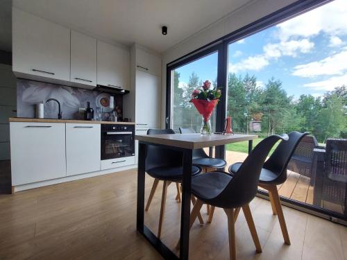 een keuken met een tafel en stoelen en een groot raam bij Ekolandia in Orneta