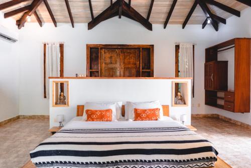 1 dormitorio con 1 cama blanca grande con almohadas de color naranja en Playa Cielo Beach Front hotel, en Santa Teresa Beach